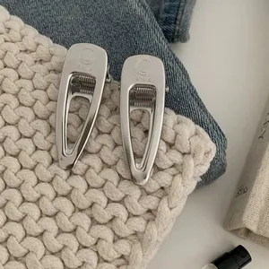Detailed view of silver metal smile hair clips on blue denim and white knit fabric