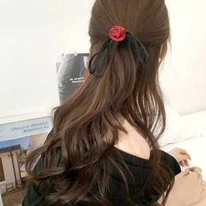 Detail of red rose ribbon scrunchie on brown wavy hair with elegant velvet texture