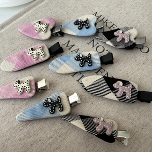 Detailed close-up of cute polka dot puppy hair clips on plaid fabric background