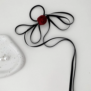 Detail of elegant burgundy rose hair scrunchie with long black ribbons on white background