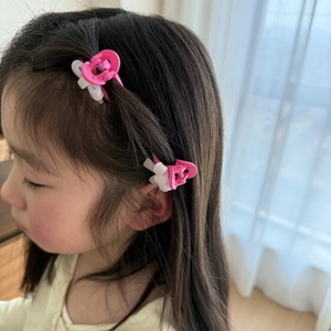 Détail de pinces à cheveux rose et blanc en forme de nœud sur une coiffure de petite fille
