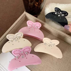 Détail de pinces à cheveux papillon mates avec strass en coloris beige et rose