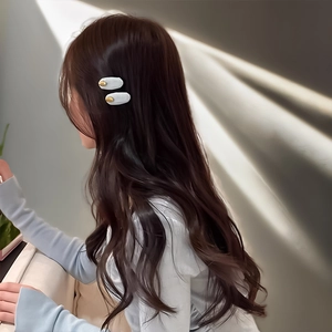 Close-up of matte light blue hair clips with gold metal accents on a model's hair