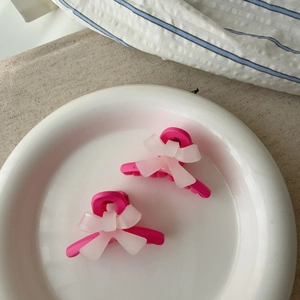 Gros plan de petites pinces à cheveux noeud rose sur une assiette blanche en céramique