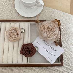Detail view of handmade rose hair claws with matte fabric petals and pearl accents on a tray