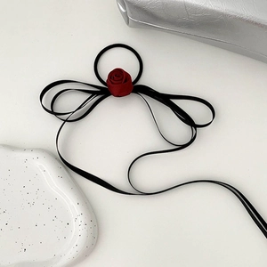 Detail of burgundy satin rose hair tie with long black streaming ribbons for back buns