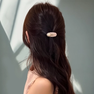 Detail of pink tweed hair clip with pearl embellishment on a half-up hairstyle