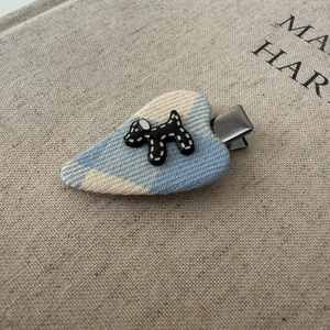 Close-up of heart-shaped knit hair clip with polka dot dog resin charm and duckbill clip