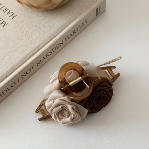 Detail of vintage fabric roses on an amber-tone hair claw with a soft beige background