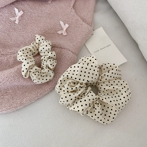Détail de chouchous crème à pois sur un pull rose doux avec étiquette lune boutique