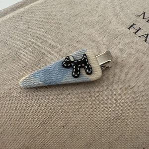 Detailed macro view of a knitted blue fabric hair clip with a spotted puppy charm decoration