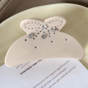 Pince à cheveux crème en forme de nœud avec strass brillants vue de près élégante