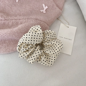 Gros plan d'un chouchou à pois crème avec texture de tissu doux et plis élégants