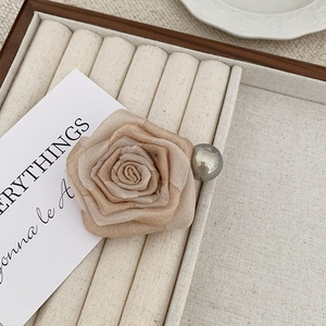 Detailed close-up of champagne fabric rose hair claw clip with metallic bead accents
