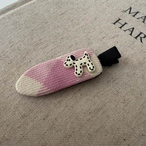 Detail of a pink knitted hair clip with a cute cream-colored polka dot puppy decoration