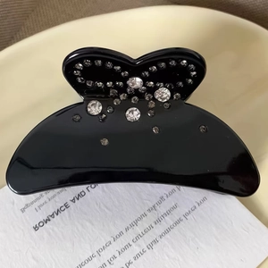 Détail d'une pince à cheveux noire ornée de strass brillants blancs et gris fumé