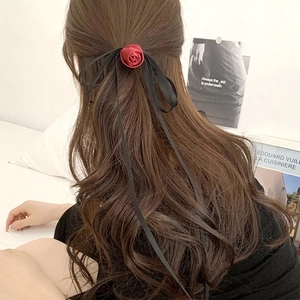 Elegant burgundy rose hair scrunchie with long black silk ribbons on wavy brown hair