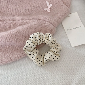 Texture détaillée du chouchou crème à pois sur un tissu en maille douce
