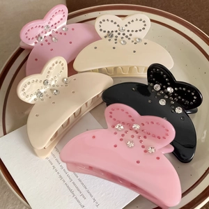 Détail d'un lot de 5 pinces à cheveux papillon avec strass disposées sur un plateau en céramique