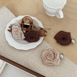 Detailed view of dried rose hair clips with pearls and acrylic claw on a ceramic plate