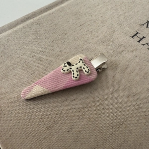 Close-up of a pink checkered hair clip featuring a cute spotted puppy resin decoration