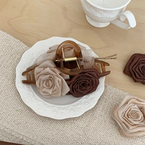 Detailed view of handmade fabric roses on a brown claw clip displayed in a porcelain plate