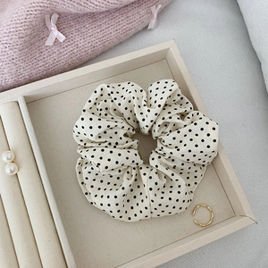 Gros plan du chouchou à pois crème avec texture en coton doux et plis élastiques fins