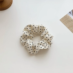 Gros plan sur un chouchou à pois crème avec texture de tissu plissé et souple