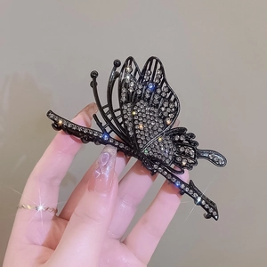 Elegant hollow butterfly hair claw clip with rhinestones shown in a hand-held view