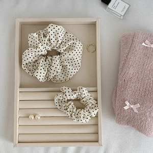 Détails de chouchous en tissu beige à pois sur un plateau avec des bijoux