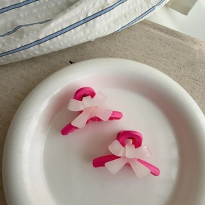 Lot de deux pinces à cheveux à nœud rose et blanc pour frange sur plat en céramique