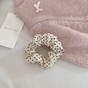 Chouchou crème à pois noirs élégant posé sur un fond en tricot rose doux