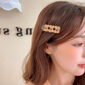 Detail view of a cute brown bear hair clip worn on wavy hair for a stylish side hairstyle