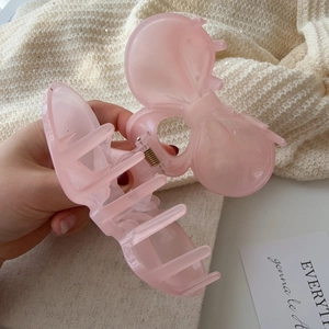 Detail of a creamy pink resin bow hair claw clip showing its smooth pearlescent texture