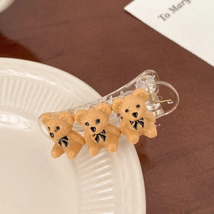 Detail view of transparent hair claw clip with three matte brown teddy bear figurines
