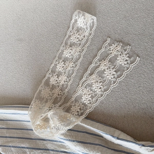 Close-up of beige floral lace hair ribbon with delicate embroidery and wavy edges