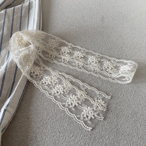 Detail of ivory floral embroidery lace ribbon with scalloped edges for DIY sewing