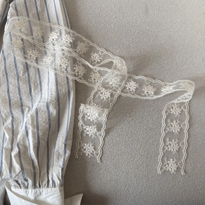 Detailed macro view of delicate cream floral lace ribbon with intricate hollow embroidery