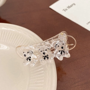 Close-up of a clear acrylic claw clip with three cute teddy bears and black bows
