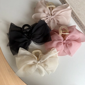 Close-up of elegant chiffon organza bow hair claws in beige, pink, black, and white