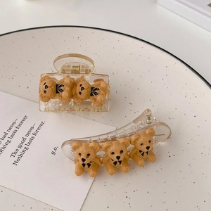 Detail of brown teddy bear hair clips with black bow ties on a dotted white tray