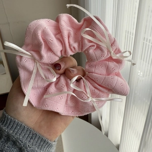 Detail of pink knit hair scrunchie with white ribbon bows in balletcore style