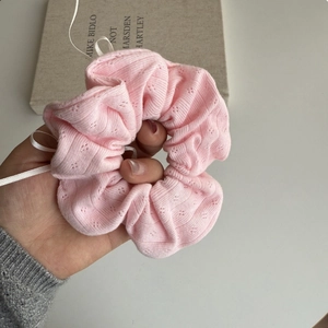 Detailed close-up of pink knit scrunchie with diamond hollow pattern and white ribbon