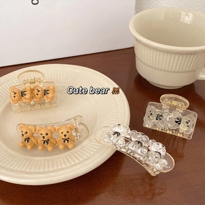 Detail of four cute bear hair clips in brown and clear resin with black bow accents