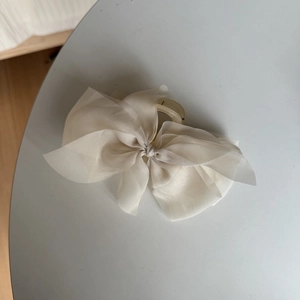 Detailed view of the layered cream organza bow and transparent hair claw clip