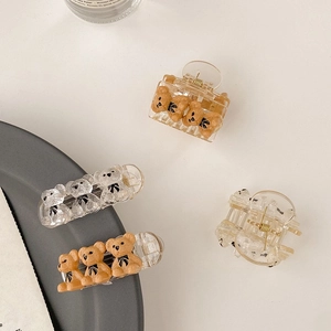 Detail view of teddy bear hair clips in amber and clear acrylic with bow accents