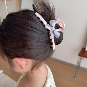 Pince à cheveux en résine rose avec un nœud à pois porté sur un chignon élégant