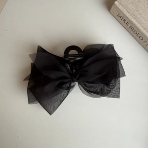 Detailed macro view of the layered black chiffon mesh fabric on a stylish shark hair claw