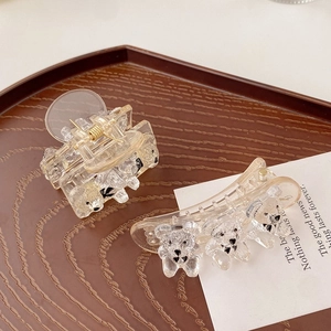 Close-up of clear acrylic hair clips with cute bear designs on a wooden tray