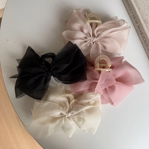 Detail of four chiffon organza bow hair claws in black, champagne, pink, and cream white
